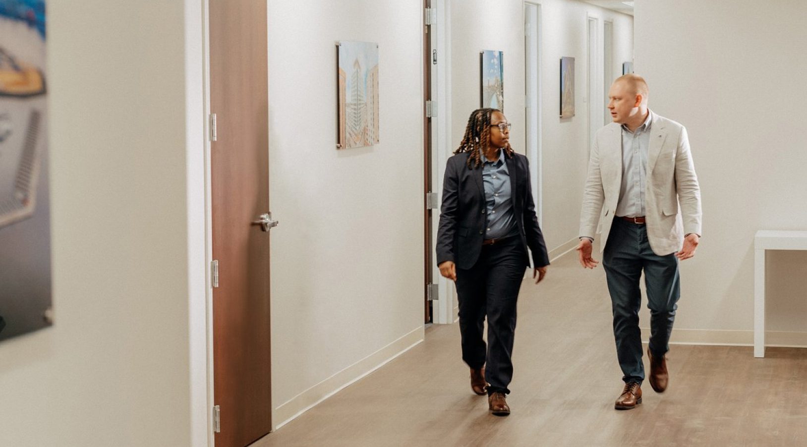 Two people walking through office